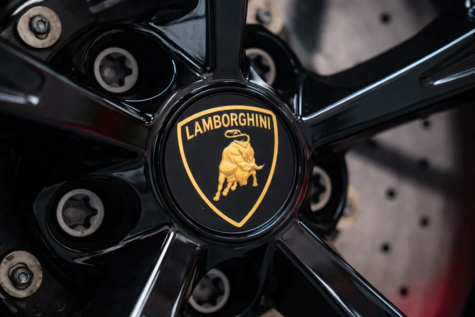 Close-up of a Lamborghini wheel featuring the iconic bull logo, photographed during a professional service visit, representing lamborghini repair near me at a high-end auto workshop.