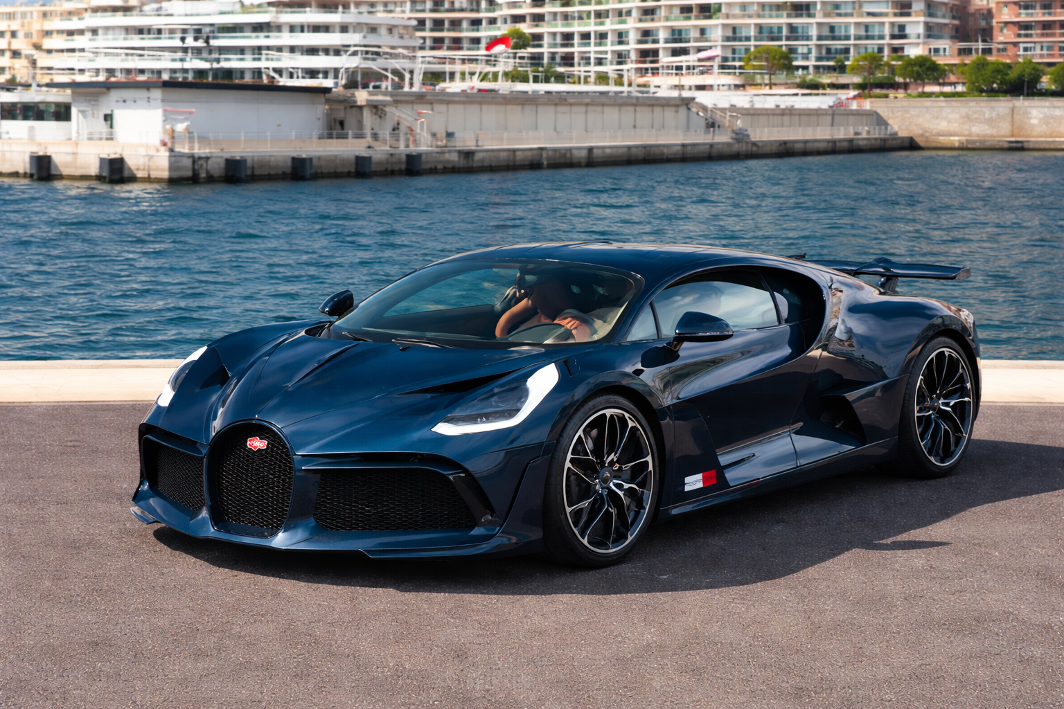 Bugatti Divo parked by a waterfront marina with the Bugatti logo visible on the grille, representing premium Bugatti Divo repair and maintenance service.