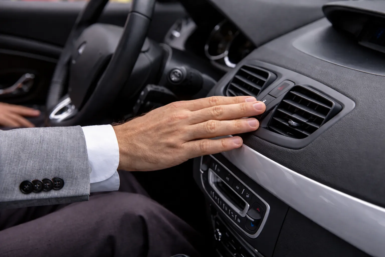 Close-up of a driver adjusting the dashboard air vent and AC controls inside a vehicle, illustrating land rover ac gas refill and cooling system service.