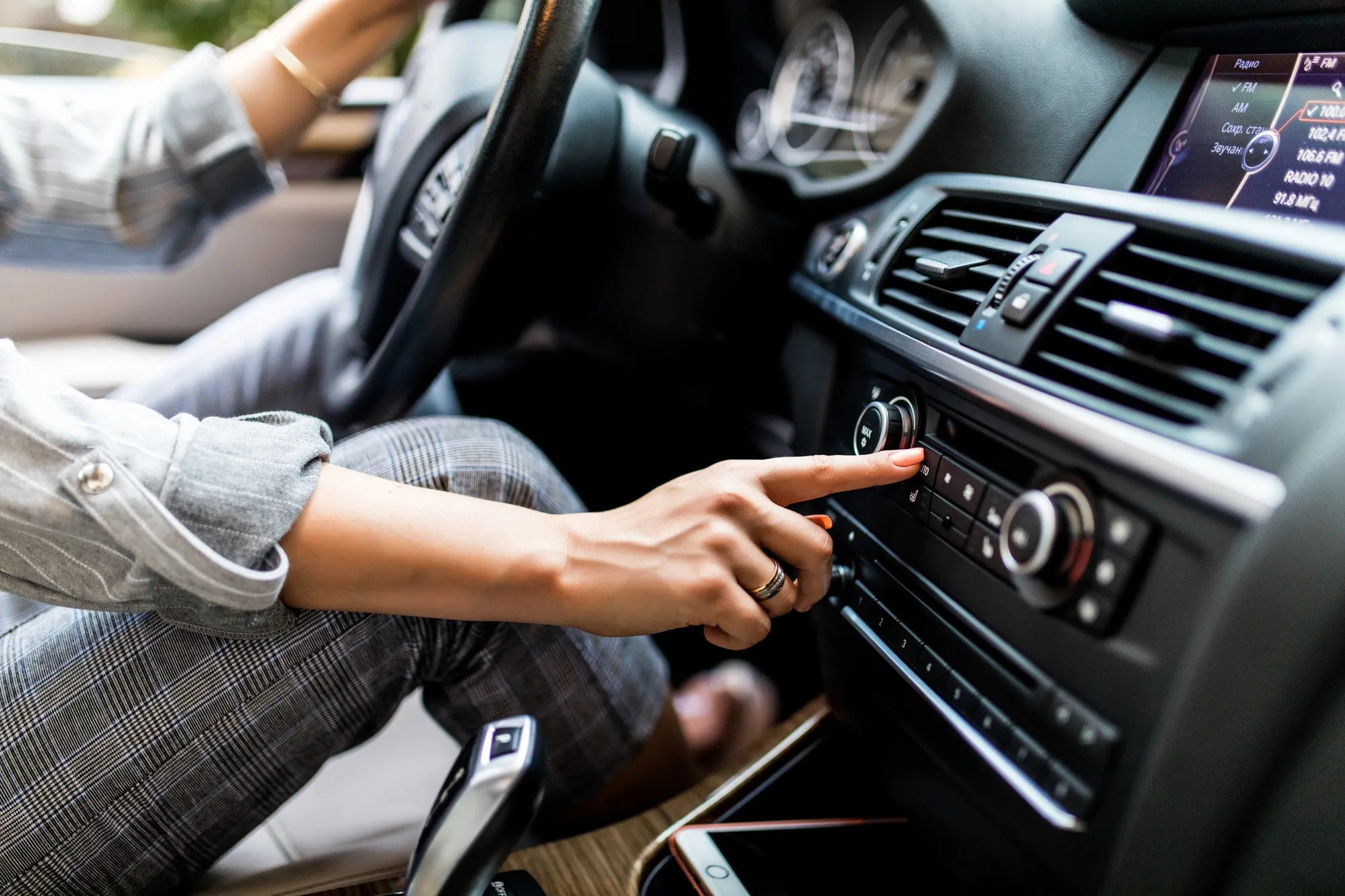 Driver adjusting the car’s climate control system on the dashboard while dealing with a car AC not cooling in Dubai during hot weather.
