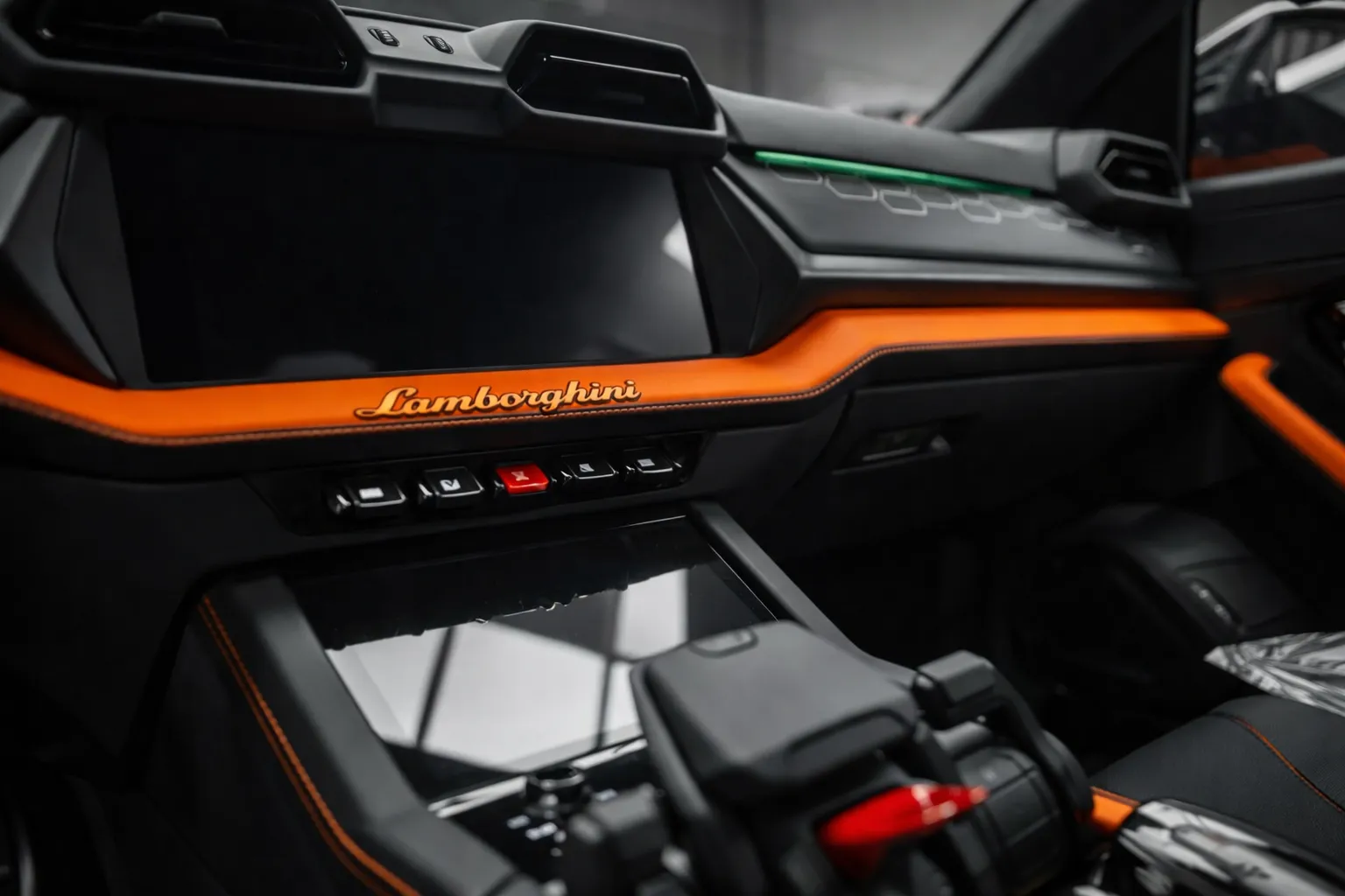 Close-up of a Lamborghini cockpit showing the orange-accent dashboard with “Lamborghini” branding, a modern infotainment screen, and the center console controls - ideal for promoting premium lamborghini ac services with a luxury finish.