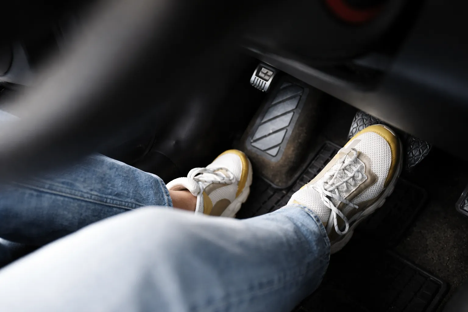Driver pressing the brake pedal inside a car, highlighting braking performance while considering brake pad replacement cost for safe and responsive driving.