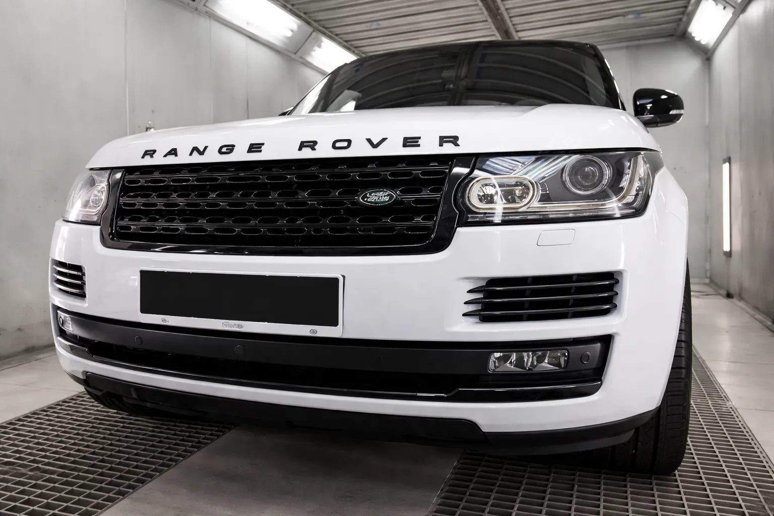 Front view of a white Range Rover inside a professional workshop, highlighting its grille and headlights, representing high-quality Range Rover service Dubai.