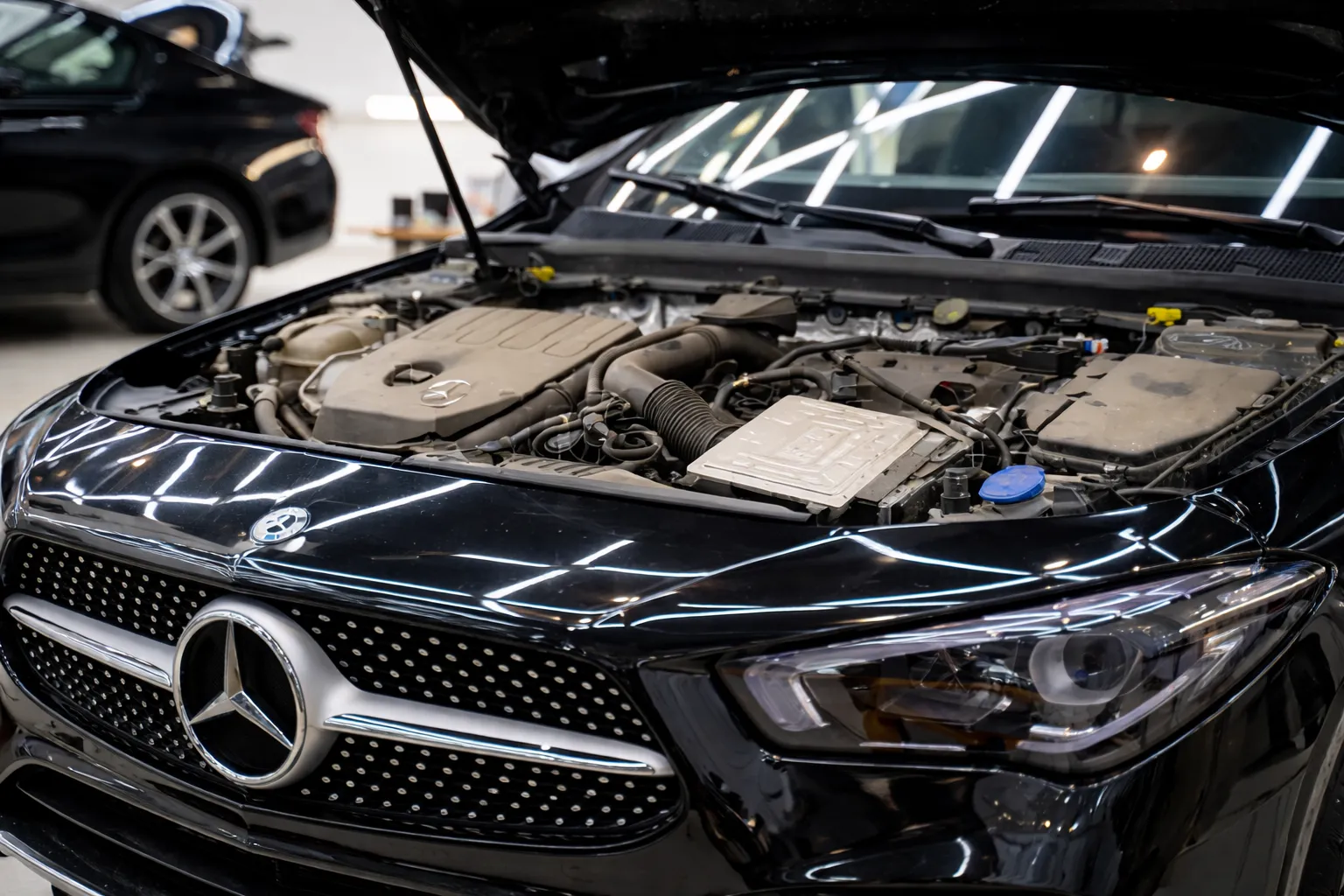 Open hood of a Mercedes car revealing the engine bay inside a modern workshop, ideal for those searching for Mercedes car repair near me.