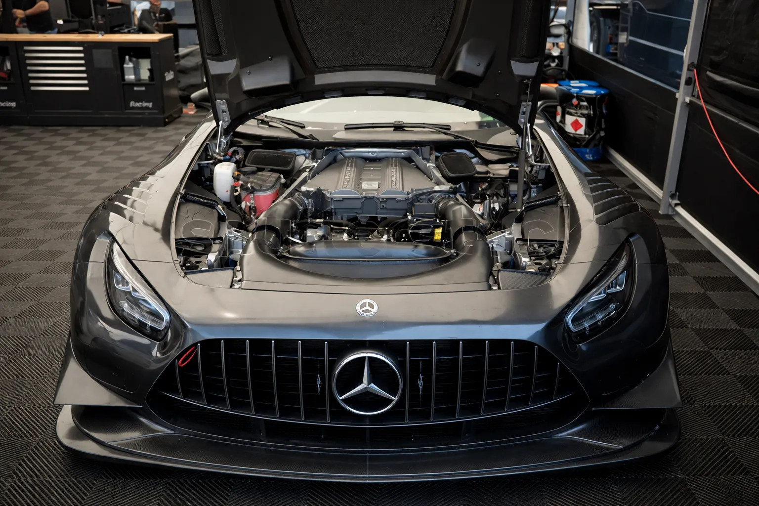 Front view of a Mercedes-AMG with the hood open inside a modern garage, showcasing engine inspection and maintenance at a professional Mercedes repair workshop in Dubai.