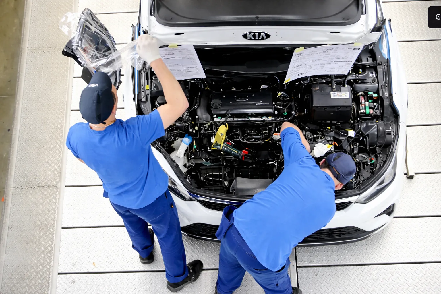 Technicians working on the engine of a Kia car in a modern workshop, representing professional services at a KIA service center Dubai.