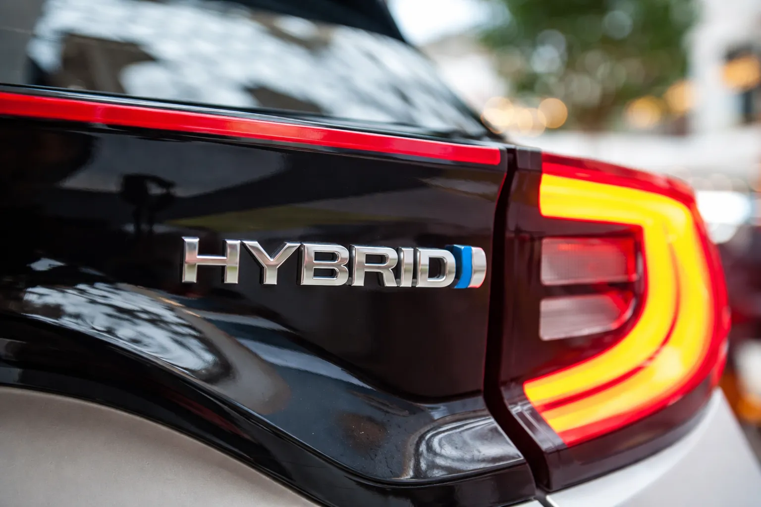 Close-up of a hybrid car badge and rear taillight, highlighting modern design while relating to common hybrid car problems affecting performance and maintenance.