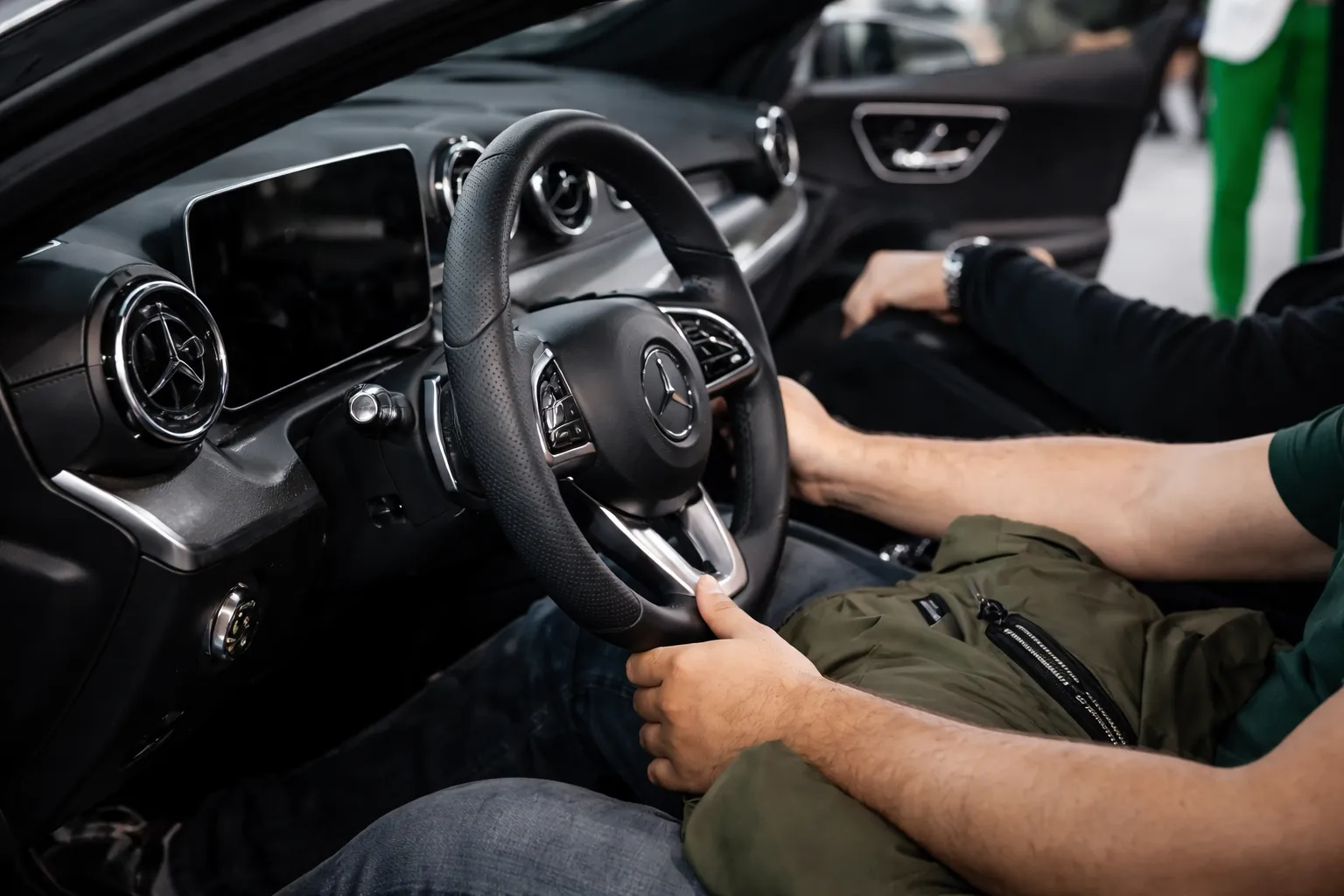 Driver seated inside a Mercedes car holding the steering wheel with the logo visible, showcasing a premium interior typical of a best Mercedes repair shop in Al Quoz.