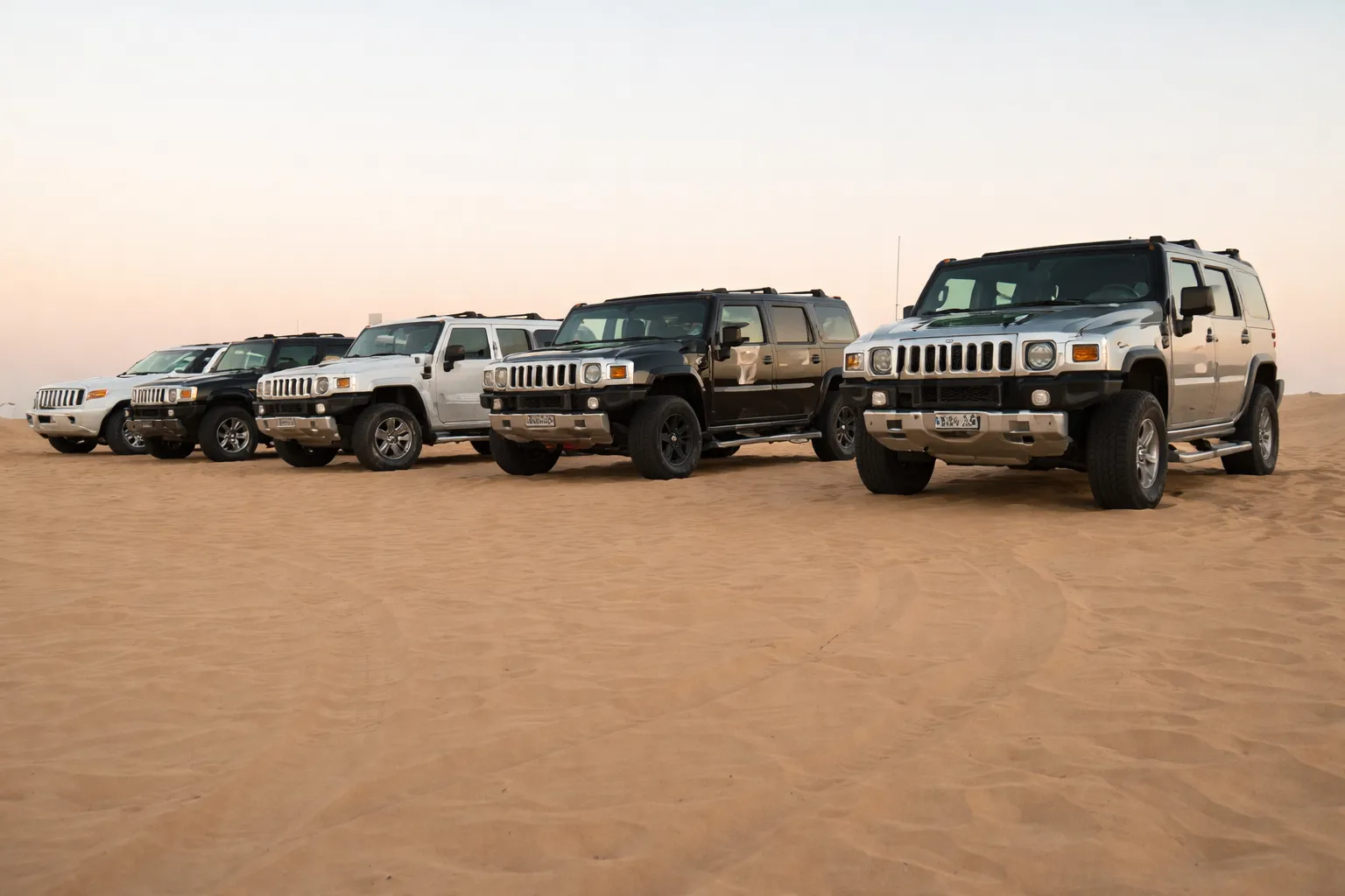 Line of Hummer SUVs parked on desert sand, showcasing off-road capability and durability, often maintained through professional Hummer service Dubai.