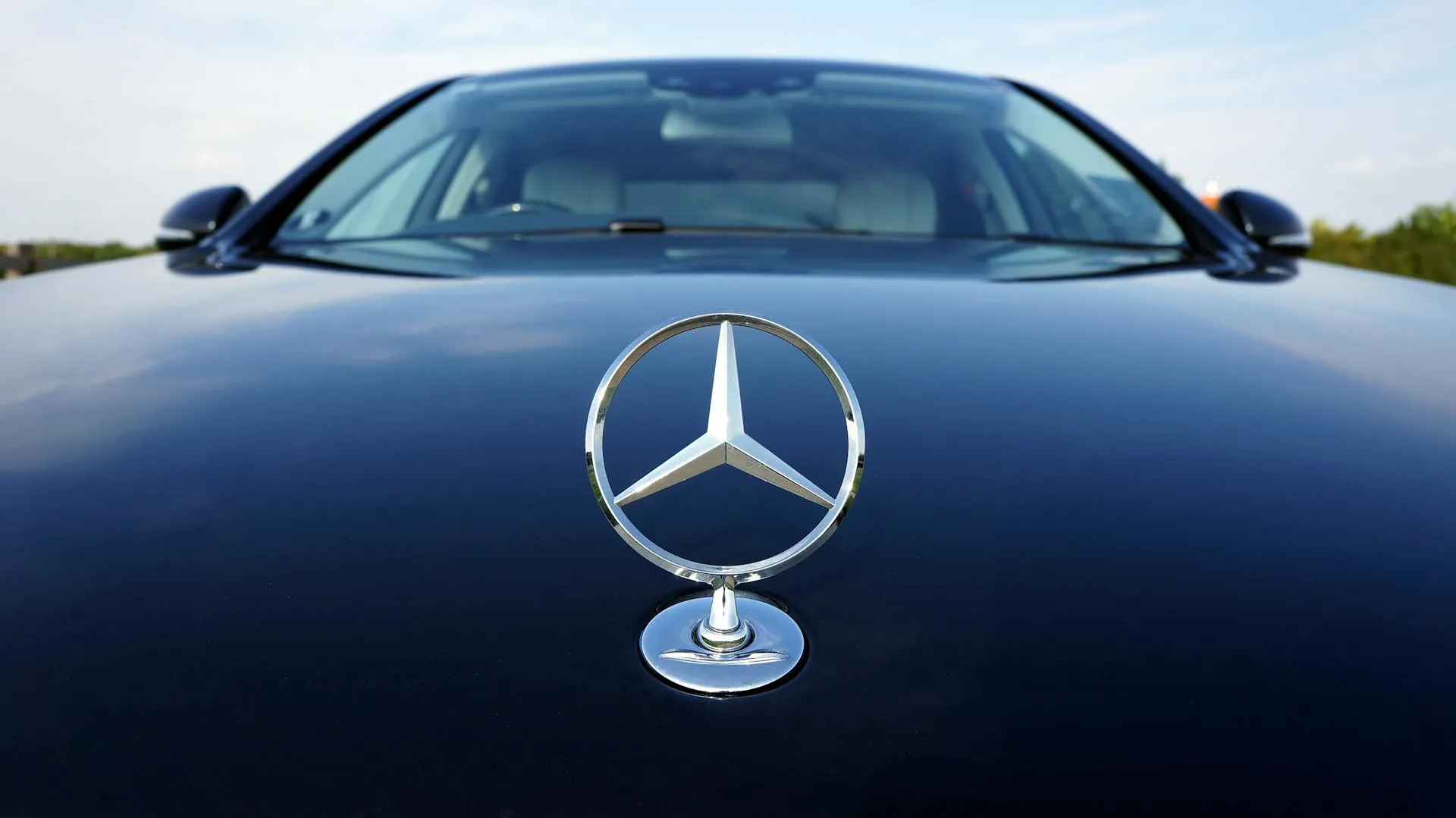 Close-up of a Mercedes-Benz hood ornament on a sleek black car, symbolizing premium quality and service at the best Mercedes workshop.
