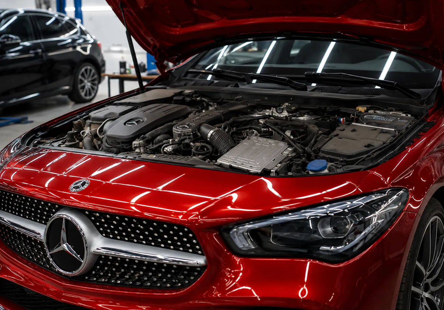 Mercedes vehicle with the hood open inside a modern workshop, undergoing professional Mercedes repair in Dubai as technicians inspect and service the engine components.